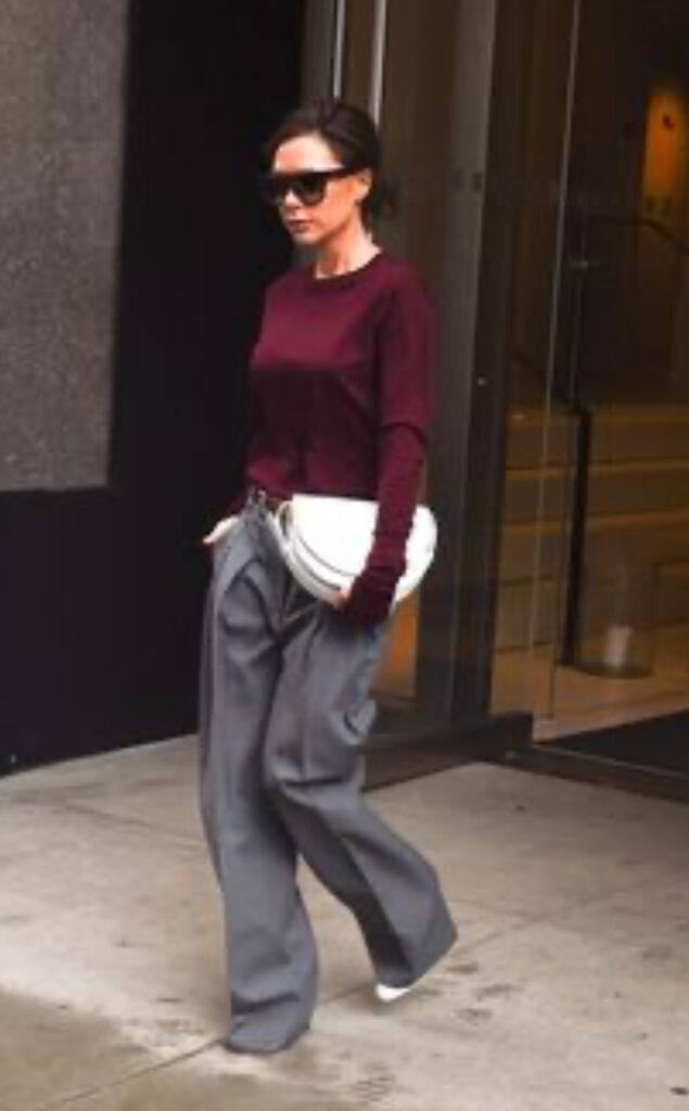 voctoria Beckam indossa pantalone grigio morbido, pullover bordeaux e borsa bianca
