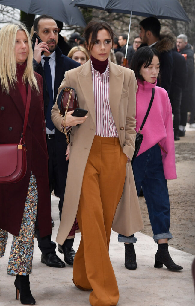 victoria beckam con cappotto, camicia a righe e lupetto