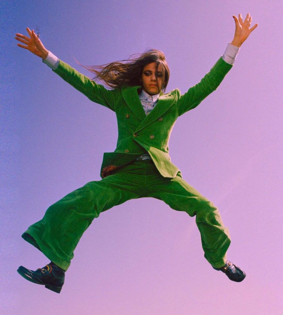 Lucio Corsi in un fotogramma mentre salta con un vestito verde di Gucci