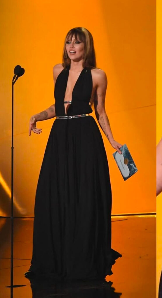 Lungo abito vaporoso tutto nero per Miley Cyrus che presenta un ospite ai Grammy. La scollatura davanti è sempre profonda