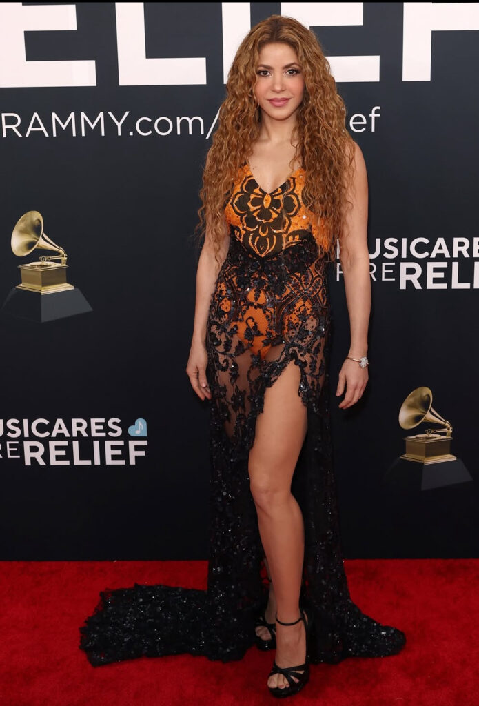shakira in un abito nero di piszzo con inserti arancioni di Etro con un profondo spacco davanti