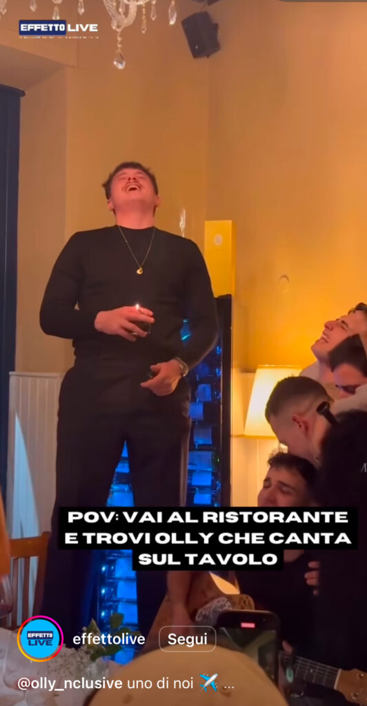Olly in piedi su un tavolo di un ristorante mentre fuma
